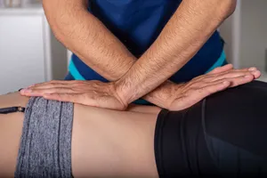 Chiropractor working on a woman's back during a spinal adjustment treatment.