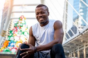 Man sitting down holding his knee as if he's in pain